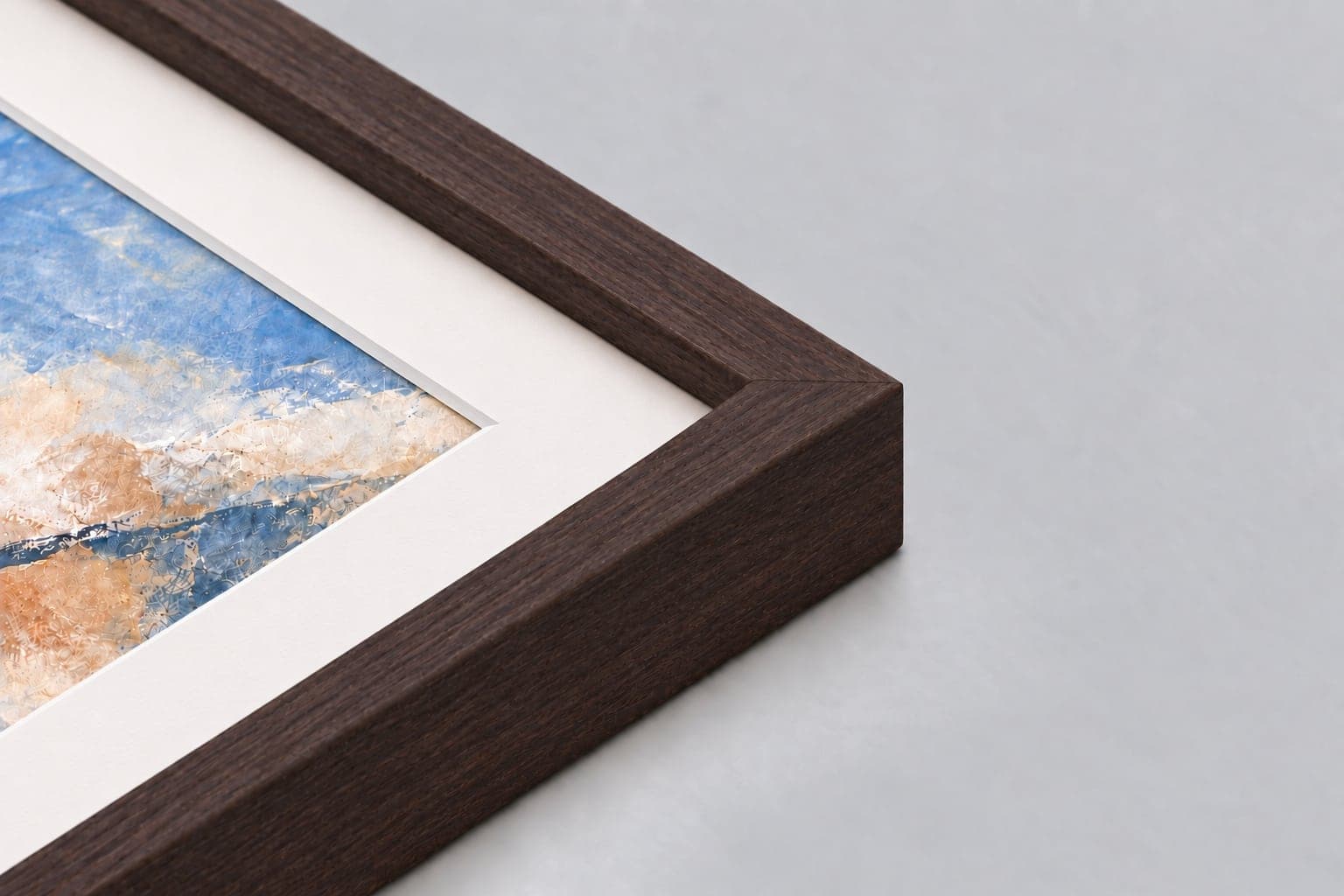 Corner of a brown closed-grain deep frame with a mount